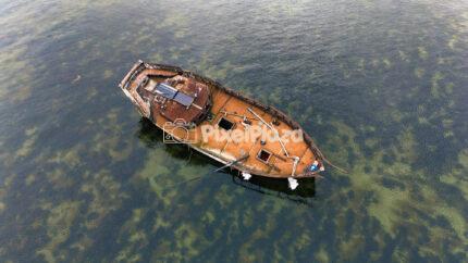 Drone View of Abandoned Shipwreck in Baltic Sea Harbor Under Cloudy Sky